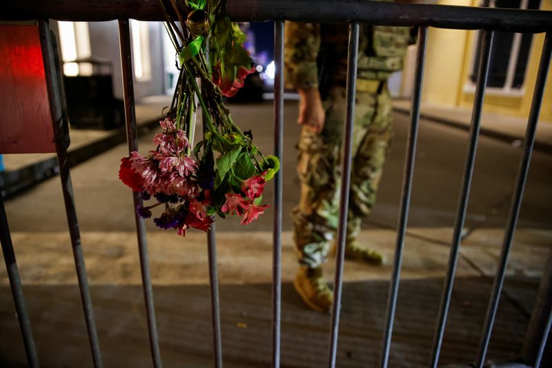 © Reuters. A military personnel stands near flowers on a fence near the scene where a vehicle drove into a crowd during New Year's celebrations, in New Orleans, Louisiana, U.S., January 1, 2025. REUTERS/Eduardo Munoz