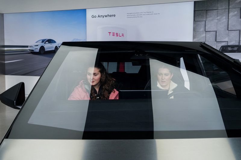 © Reuters. People sit inside a Tesla Cybertruck at a Tesla showroom in New York City, U.S., January 2, 2025. REUTERS/Adam Gray