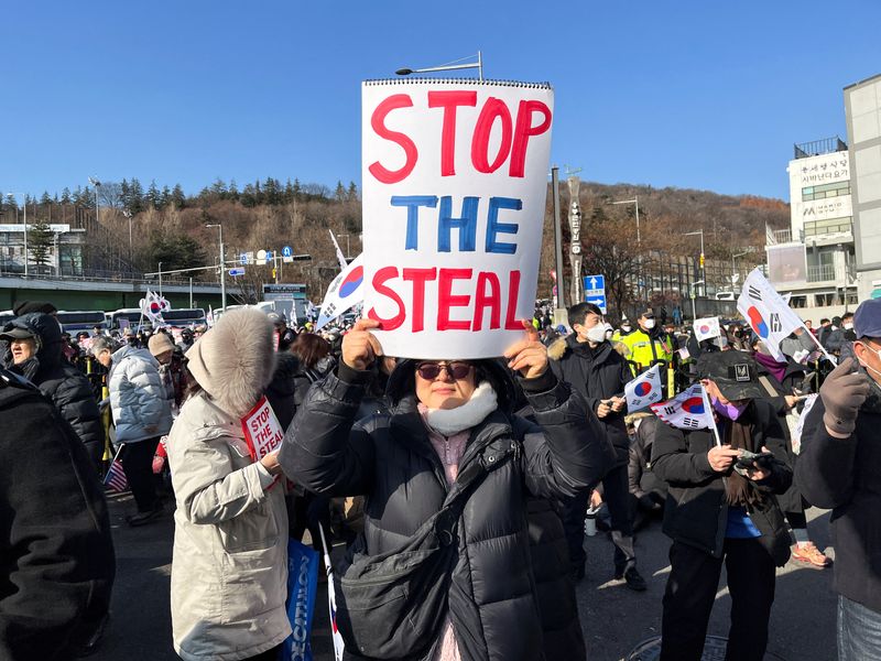 &copy; Reuters. Park Chae-yeon, 53, a supporter of the impeached South Korean President Yoon Suk Yeol, holds up a banner that reads 'STOP THE STEAL' at a rally near Yoon's official residence as he faces potential arrest after a court on Tuesday approved a warrant for his