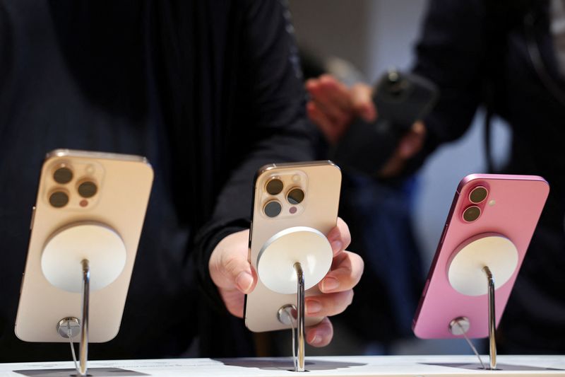 © Reuters. FILE PHOTO: A man checks an iPhone 16 Pro as the new iPhone 16 series smartphones go on sale at an Apple store in Beijing, China September 20, 2024. REUTERS/Florence Lo/File Photo