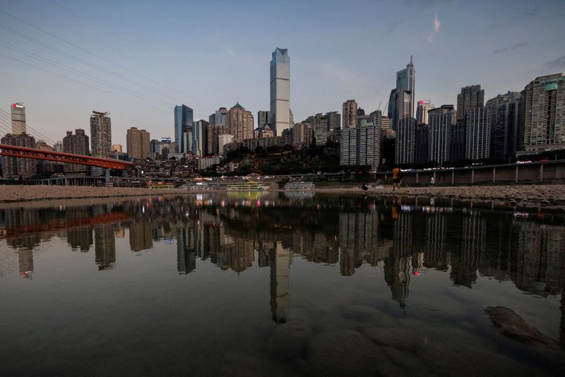 © Reuters. FILE PHOTO: A city skyline is reflected in a pool of water left on the dry bed of the Yangtze River, a tributary of the Jialing River, which is approaching record low water levels during a regional drought in Chongqing, China, August 20, 2022. REUTERS/Thomas Peter/File Photo