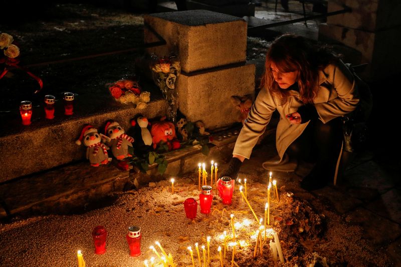 © Reuters. A woman plants a candle during a silent protest next to the scene of a mass shooting, in Cetinje, Montenegro, January 5, 2025. REUTERS/Stevo Vasiljevic