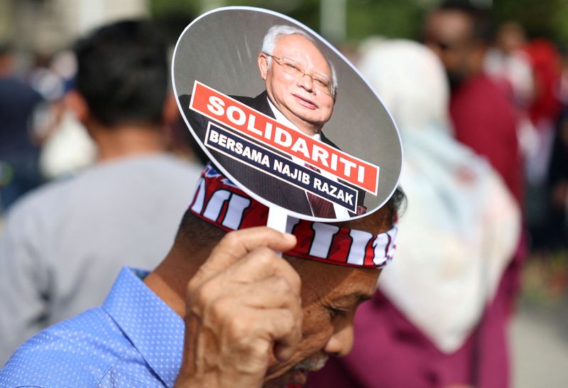 © Reuters. A supporter of former Malaysian Prime Minister Najib Razak holds a hand fan bearing his image outside the Court of Appeal, where his case is being heard in Putrajaya, Malaysia, January 6, 2025. REUTERS/Hasnoor Hussain