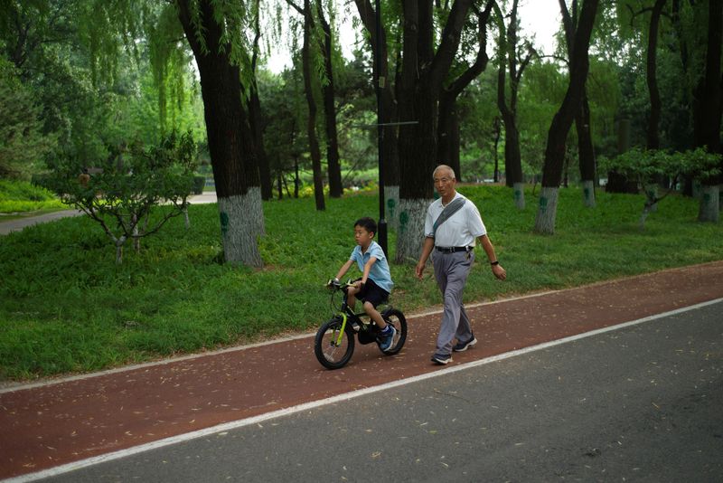 &copy; Reuters. FILE PHOTO: An elderly person walks next to a child at a park on a summer day in Beijing, China May 22, 2024. REUTERS/Tingshu Wang/File Photo