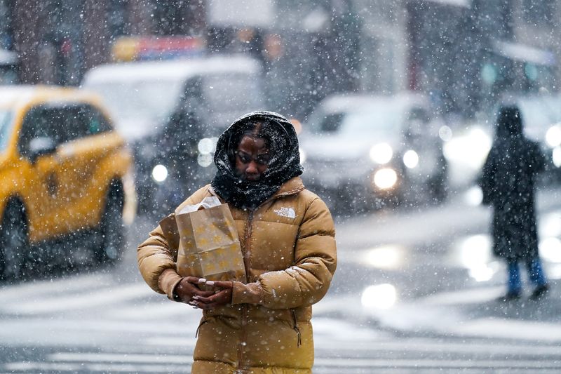 © Reuters. A person crosses the street during snowfall in New York City, U.S., January 6, 2025. REUTERS/Adam Gray