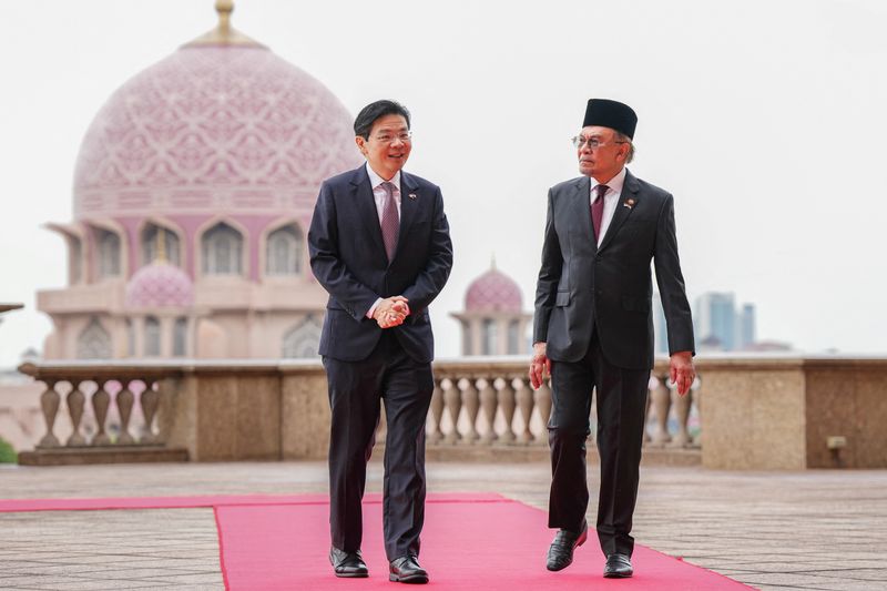 © Reuters. Singapore Prime Minister Lawrence Wong walks with Malaysian Prime Minister Anwar Ibrahim with the background of Putra Mosque during a welcoming ceremony prior to their meeting in Putrajaya, Malaysia, January 7, 2025. Vincent Thian/Pool via REUTERS