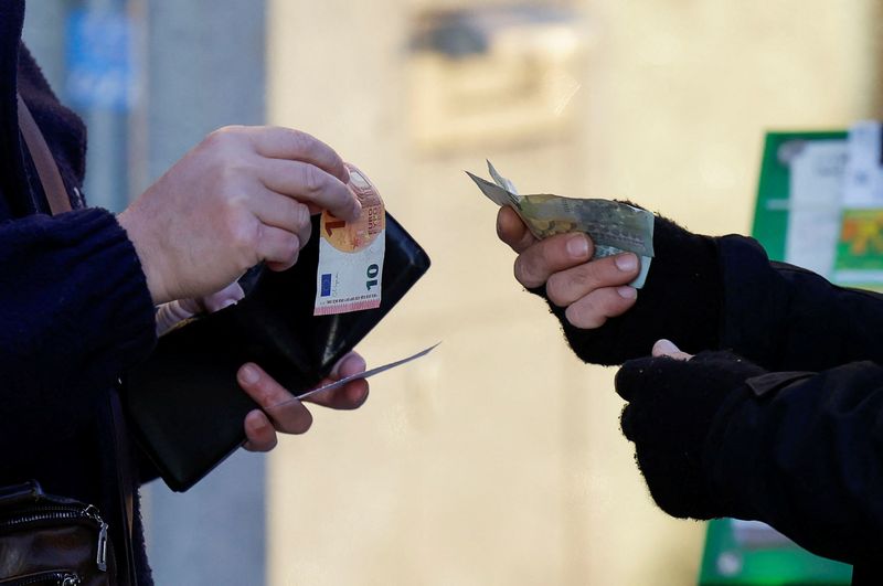 &copy; Reuters. Un cliente cambia una banconota da dieci euro con due da cinque euro con un venditore ambulante, a Ronda, in Andalusia, Spagna. 30 dicembre 2024. REUTERS/Jon Nazca