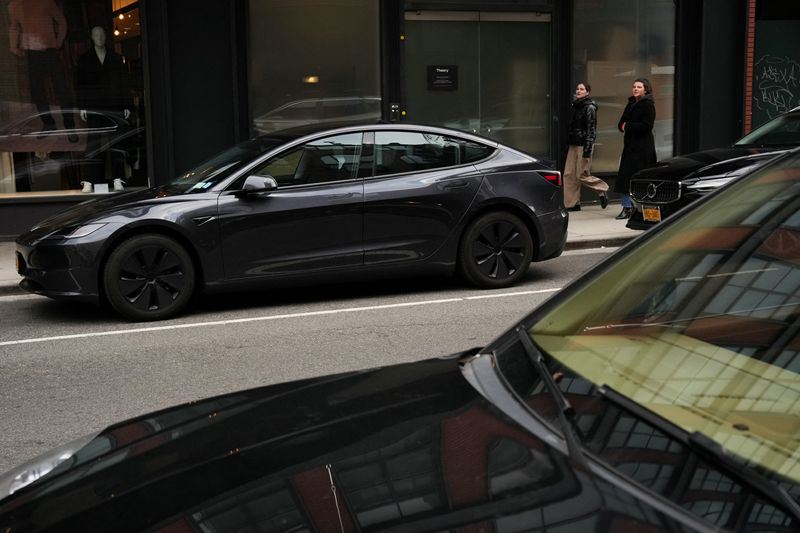 © Reuters. FILE PHOTO: People walk past a Tesla car parked in the Meatpacking District of New York City, U.S., January 02, 2025. REUTERS/Adam Gray/File Photo