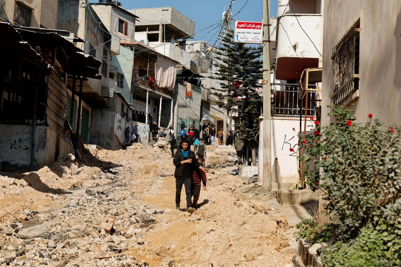 © Reuters. People gather at a damaged road, in the aftermath of an Israeli raid at the Al-Faraa camp near Tubas, in the Israeli-occupied West Bank, January 7, 2025. REUTERS/Raneen Sawafta