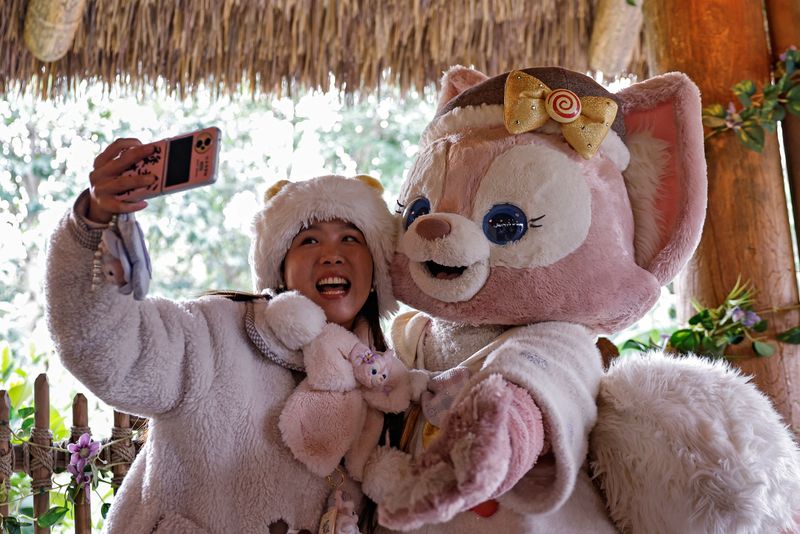 © Reuters. A fan takes a selfie with a performer dressed as the character LinaBell, a pink fox character from the Disney series 'Duffy and Friends', at Shanghai Disneyland, in Shanghai, China December 23, 2024. REUTERS/Tingshu Wang