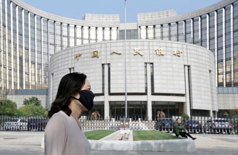 © Reuters. FILE PHOTO: A woman walks past the headquarters of the People's Bank of China (PBOC), the central bank, in Beijing, China September 28, 2018. REUTERS/Jason Lee/File Photo