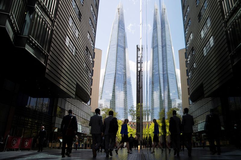 © Reuters. FILE PHOTO: City workers are reflected in a window as they pass near the Shard building in London, Britain April 28, 2015.  REUTERS/Neil Hall/File Photo