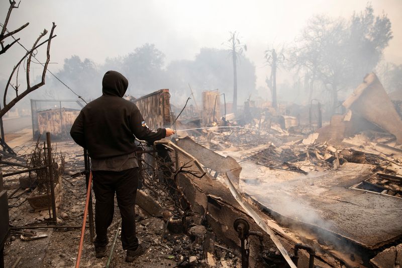 &copy; Reuters. A resident uses a hose as wildfires spread through the neighbourhood, in Altadena, California, U.S. January 8, 2025. REUTERS/Zaydee Sanchez