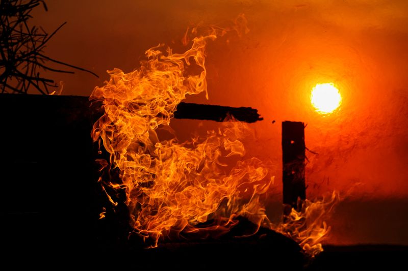 © Reuters. Flames rise from a beachfront home along the road to Malibu, as powerful winds fueling devastating wildfires in the Los Angeles area force people to evacuate, California, U.S. January 8, 2025. REUTERS/Mike Blake    