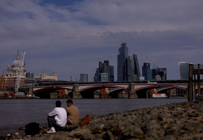 © Reuters. FILE PHOTO: People sit on the bank of the river Thames in front of the financial district in London, Britain, August 27, 2024. REUTERS/Hannah McKay/File Photo