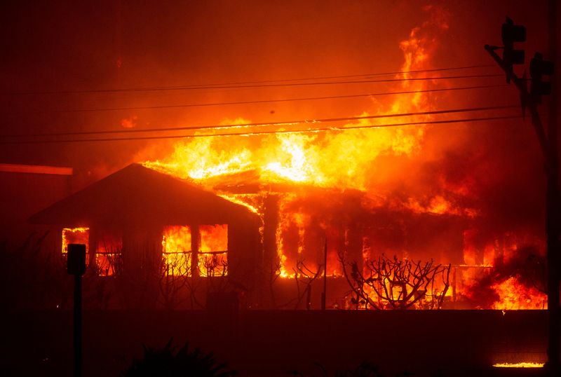 &copy; Reuters. Un incendio avvolge una struttura mentre il Palisades Fire brucia durante una tempesta di vento nella zona ovest di Los Angeles, California, Stati Uniti, 7 gennaio 2025. REUTERS/Ringo Chiu