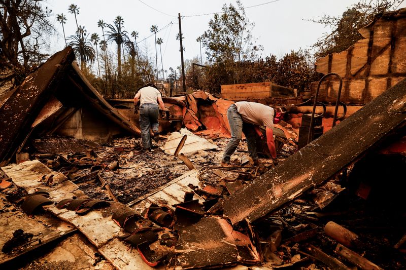 © Reuters. People search through the remains of a house that was burnt down by the Eaton Fire, as powerful winds fueling devastating wildfires in the Los Angeles area force people to evacuate, in Altadena, California, U.S. January 9, 2025.  REUTERS/Fred Greaves