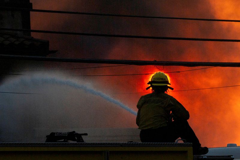 © Reuters. A firefighter battles the Palisades Fire as it burns during a wind storm on the west side of Los Angeles, California, US on January 8, 2025. REUTERS/Ringo Chiu 