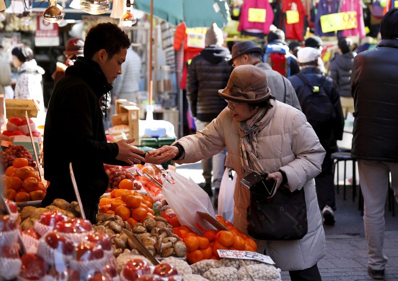 © Reuters. FILE PHOTO: A woman pays money as she buys fruits outside a vegetable store at Ameyoko shopping district in Tokyo, Japan, January 27, 2016.  REUTERS/Yuya Shino/File Photo