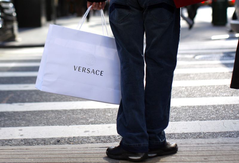 © Reuters. FILE PHOTO: A shopper holds a handbag from luxury designer Versace as she stands at an intersection near 5th Avenue in New York, November 19, 2008. REUTERS/Mike Segar/ File Photo