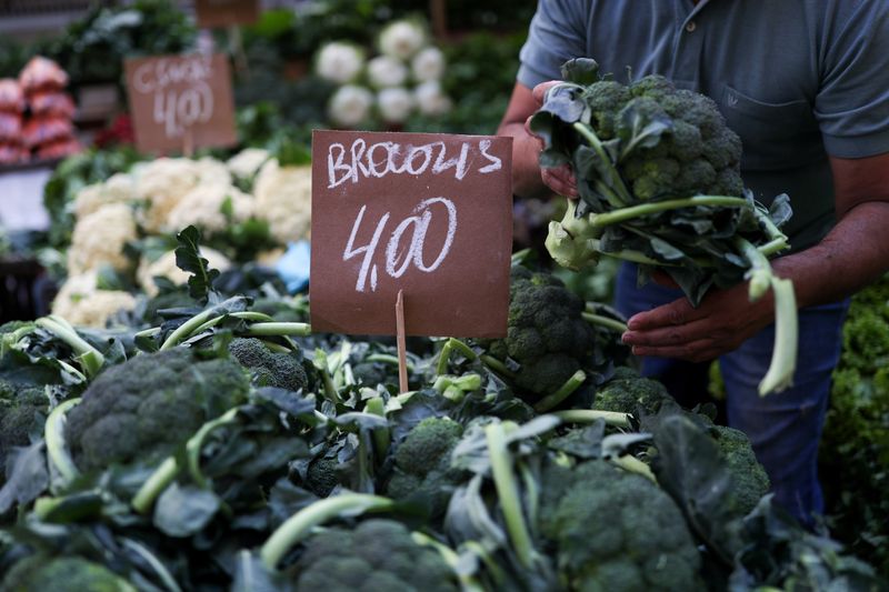 © Reuters. FILE PHOTO: A man holds a broccoli as the price is displayed at a weekly street market in Rio de Janeiro, Brazil July 8, 2021. REUTERS/Amanda Perobelli/File Photo