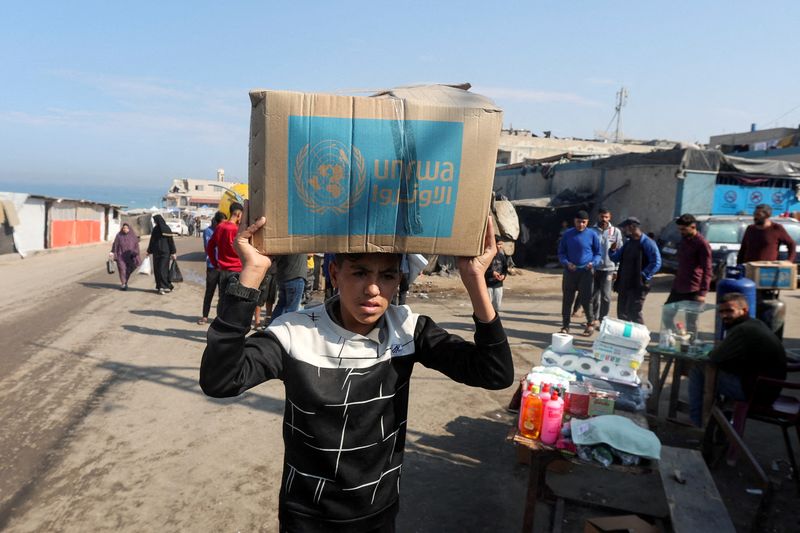 &copy; Reuters. FILE PHOTO: A Palestinian carries an aid box distributed by the United Nations Relief and Works Agency (UNRWA), amid the Israel-Hamas conflict, in Deir Al-Balah, central Gaza Strip, November 4, 2024. REUTERS/Ramadan Abed/File Photo