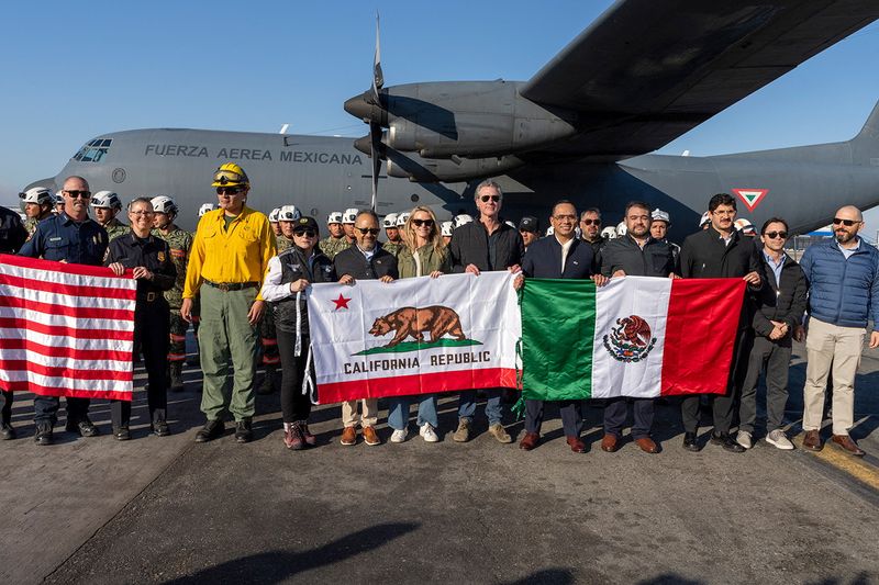 © Reuters. California Governor Gavin Newsom and other officials pose for a photo with a team of firefighters sent by Mexico to California to help teams battling raging wildfires, in Los Angeles, California, US on January 11, 2025. Office of Governor Gavin Newsom/Handout via Reuters