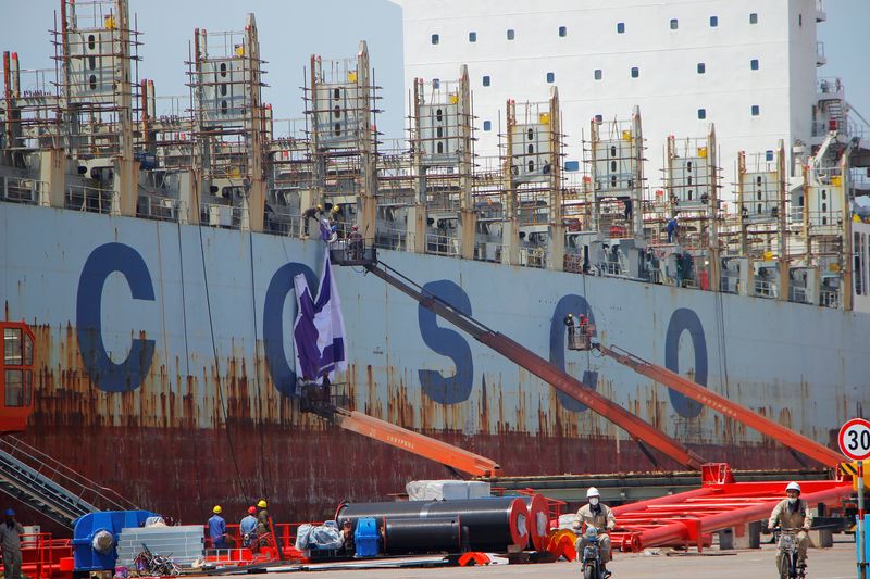 © Reuters. FILE PHOTO: Men are seen working on a China Ocean Shipping Company (COSCO) vessel under construction at a shipyard in Weihai, Shandong province, China May 16, 2019. REUTERS/Stringer/File Photo