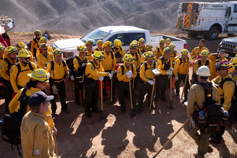 © Reuters. Firefighters from Mexico listen to a briefing before cutting a containment line in the Tarzana area during the Palisades Fire in Los Angeles, California, U.S. January 13, 2025. REUTERS/David Ryder