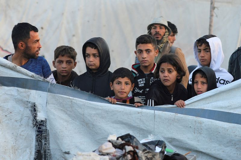 © Reuters. Palestinians look on at the site of an Israeli strike on a tent camp for displaced people, amid the ongoing conflict between Israel and Hamas, in Deir Al-Balah in the central Gaza Strip, January 14, 2025. REUTERS/Ramadan Abed