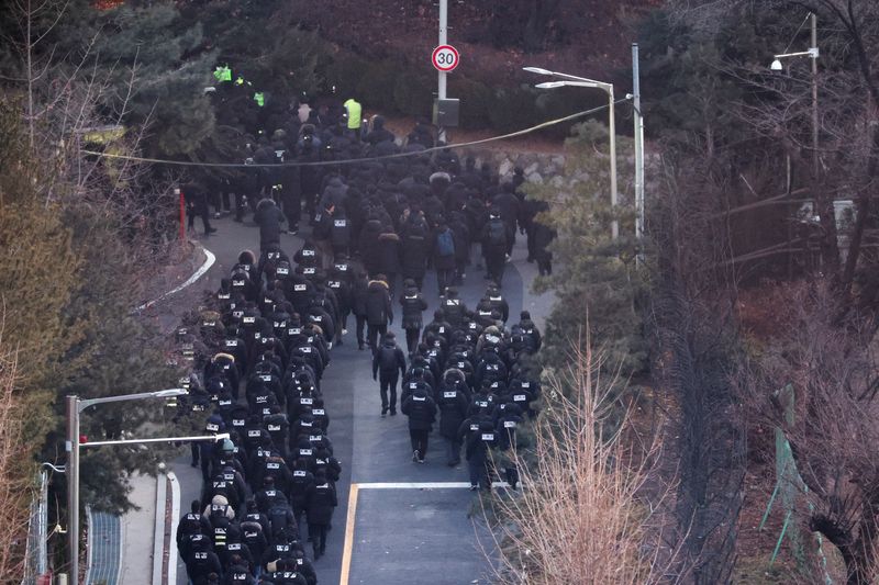 © Reuters. Police officers and investigators from the Senior Officials Corruption Investigation Bureau pass through the entrance of the official residence of deposed South Korean President Yeon Suk-yeol, as authorities seek to execute an arrest warrant, in Seoul, South Korea, January 15. 2025. Reuters/Kim Hong-ji