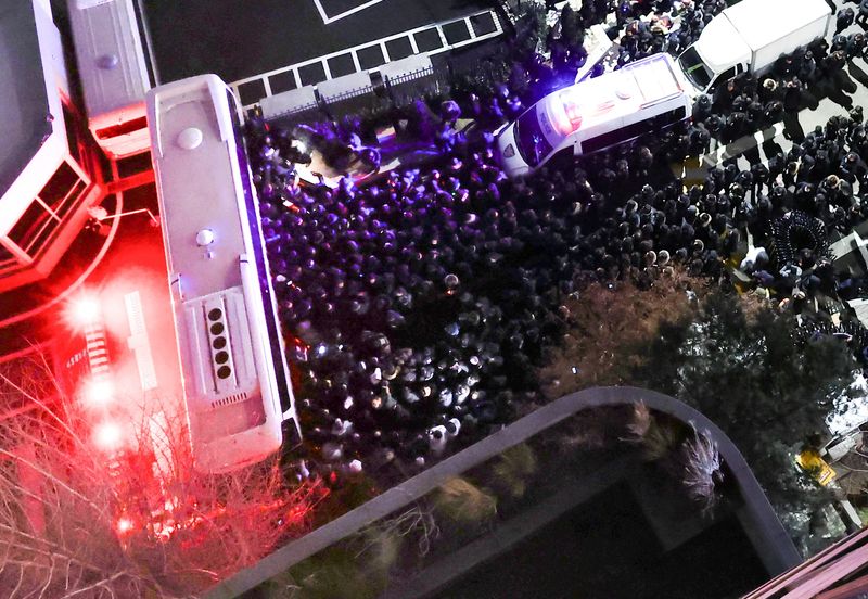 © Reuters. Police officers and investigators of the Corruption Investigation Office for High-ranking Officials gather in front of the entrance to the official residence of impeached South Korean President Yoon Suk Yeol, as authorities seek to execute an arrest warrant, in Seoul, South Korea, January 15, 2025.    Yonhap via REUTERS   