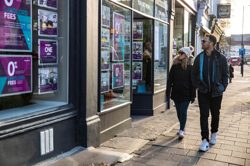 © Reuters. FILE PHOTO: People walk past a branch of Chestertons estate agents in Islington, London, Britain, December 10, 2021. Picture taken December 10, 2021. REUTERS/May James/File Photo