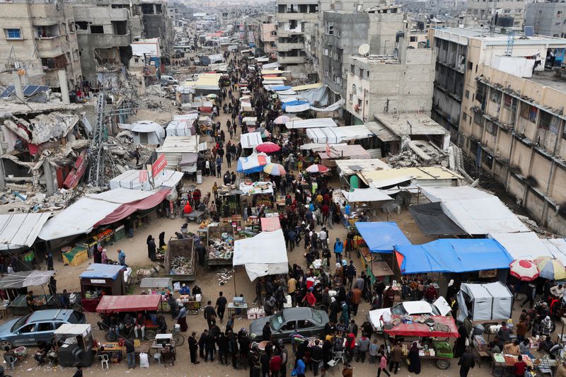 &copy; Reuters. Palestinesi camminano in un mercato mentre proseguono i negoziati per il cessate il fuoco, a Khan Younis, nel sud della Striscia di Gaza, il 15 gennaio 2025. REUTERS/Ramadan Abed