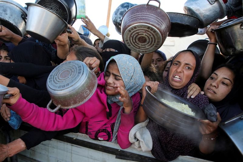 &copy; Reuters. FILE PHOTO: Palestinians gather to receive food cooked by a charity kitchen, amid a hunger crisis, as the Israel-Gaza conflict continues, in Khan Younis in the southern Gaza Strip, November 19, 2024. REUTERS/Hatem Khaled/File Photo