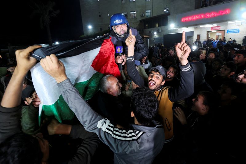 &copy; Reuters. Palestinos que comemoram notícias sobre um cessar-fogo com Israel carregam o correspondente da Al Jazeera Ashraf Amrah, enquanto ele relata ao vivo em Deir Al-Balah, no centro da Faixa de Gazan15/01/2025nREUTERS/Ramadan Abed