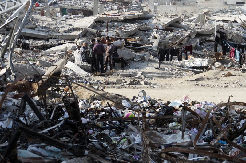 © Reuters. Palestinians stand among the rubble of homes destroyed in previous Israeli strikes amid ceasefire talks with Israel in Gaza City, January 15, 2025. REUTERS/Mahmoud Issa