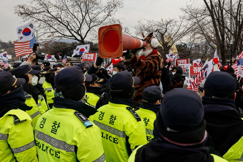 © Reuters. Pro-Yoon supporters shout during a live broadcast by a local news channel, expressing their stance on the media’s coverage during a rally outside the Seoul Detention Center in Uiwang, where impeached South Korean President Yoon Suk Yeol is held in custody, in Uiwang, South Korea, January 16, 2025. REUTERS/Tyrone Siu