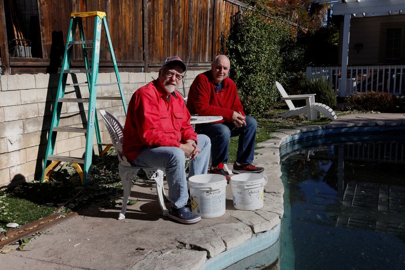 © Reuters. Neighbors Jason Salit and Billy Malone sit beside buckets that read 