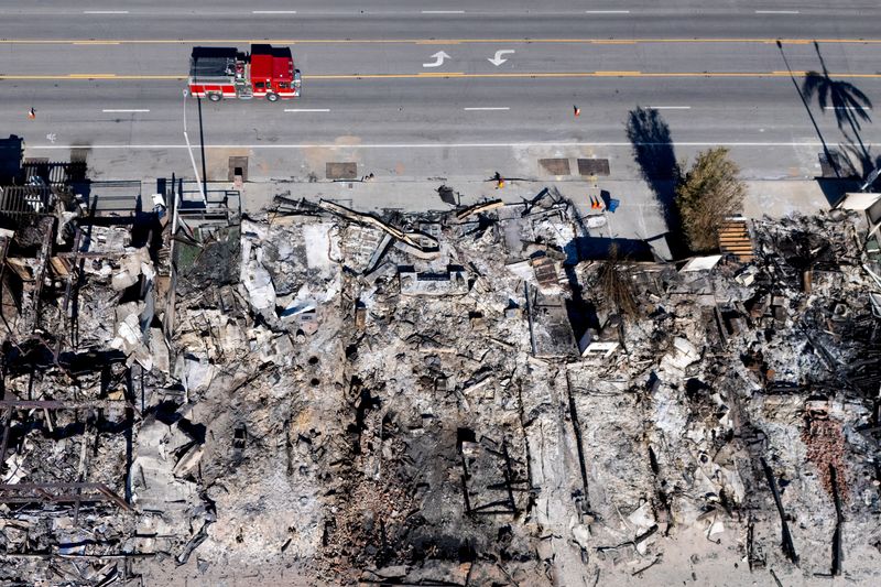 © Reuters. A drone image shows a fire truck next to a site where homes were burned by the Palisades Fire, in Malibu, California, US, January 16, 2025. REUTERS/Mike Blake