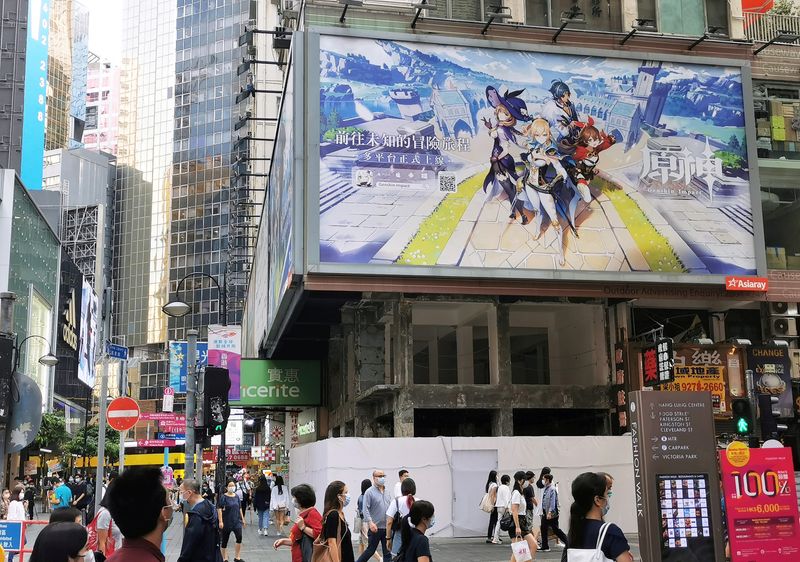 &copy; Reuters. FILE PHOTO: People walk below a billboard ad of fantasy game "Genshin Impact" from Shanghai-based developer Mihoyo in Hong Kong, China October 20, 2020. REUTERS/Pei Li/File Photo