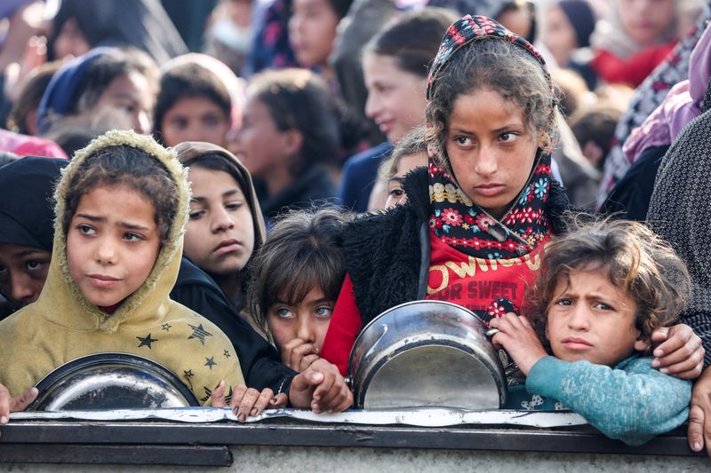 &copy; Reuters. Palestinians gather to receive food cooked by a charity kitchen, before a ceasefire between Hamas and Israel takes effect, in Khan Younis, in the southern Gaza Strip, January 17, 2025. REUTERS/Hatem Khaled   