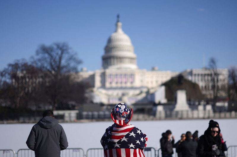 © Reuters. People stand as the U.S. Capitol is seen behind the frozen Capitol reflecting pool on the day it was announced U.S. President-elect Donald Trump's inauguration is being moved indoors due to dangerously cold temperatures expected on Monday, in Washington, U.S., January 17, 2025. REUTERS/Amanda Perobelli