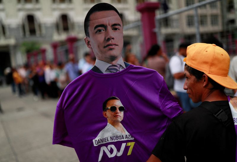 © Reuters. A supporter holds a cutout and a t-shirt of Ecuador's President and Presidential candidate for re-election, Daniel Noboa, as his campaign team hands them out on the streets, ahead of the presidential election, in Guayaquil, Ecuador, February 4, 2025. REUTERS/Henry Romero