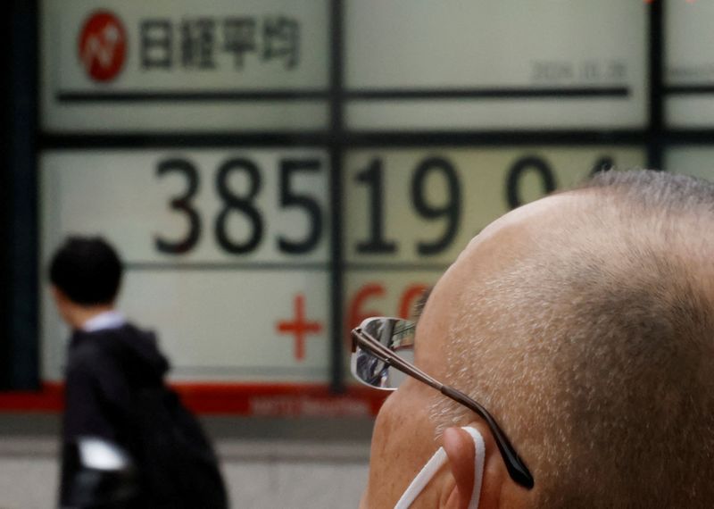 © Reuters. FILE PHOTO: A passerby walks past an electronic screen displaying the Nikkei stock average outside a brokerage in Tokyo, Japan October 28, 2024. REUTERS/Kim Kyung-Hoon/File Photo