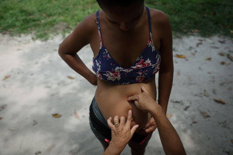 &copy; Reuters. Midwife Tabita dos Santos Moraes, 51, touches the belly of Mayleane Melo, 22, to monitor the baby's position, at the Deus e Pai community in Tefe, Amazonas state, Brazil, October 24, 2024.  REUTERS/Pilar Olivares