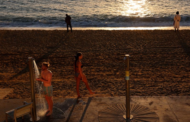 &copy; Reuters. Turista toma banho em um chuveiro da praia de Barceloneta após nadar no Mar Mediterrâneo, em Barcelonan18/01/2024nREUTERS/Nacho Doce