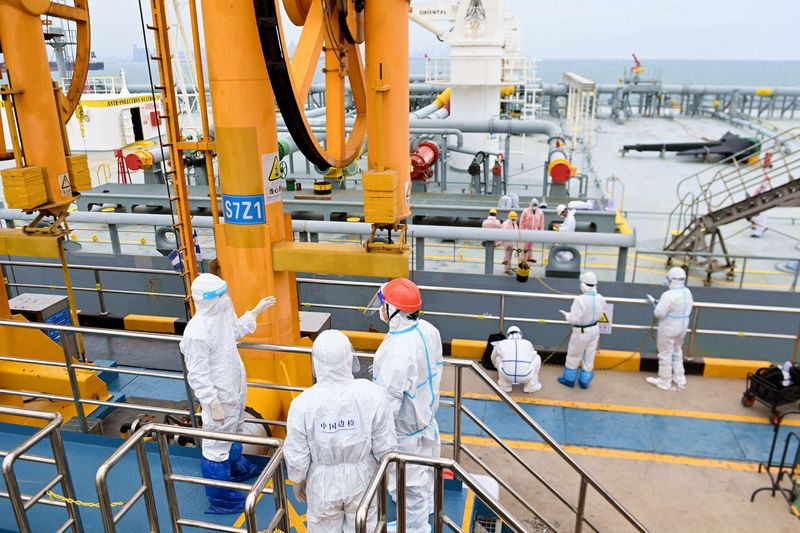 &copy; Reuters. Oficiais de inspeção de imigração em trajes de proteção verificam um petroleiro transportando petróleo importado no porto de Qingdao, província de Shandong, Chinan09/05/2022nChina Daily via REUTERS