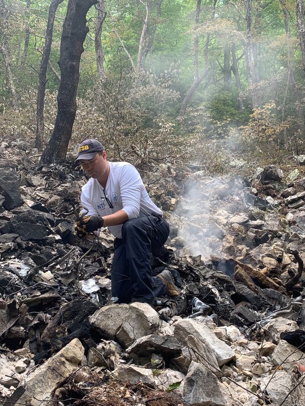 Â© Reuters. FILE PHOTO: NTSB Investigator-in-Charge Adam Gerhardt examines a fragment of wreckage at the scene of the June 4 crash of a Cessna 560 airplane near Montebello, Virginia, U.S. June 6, 2023.  NTSB/Handout via REUTERS/File Photo
