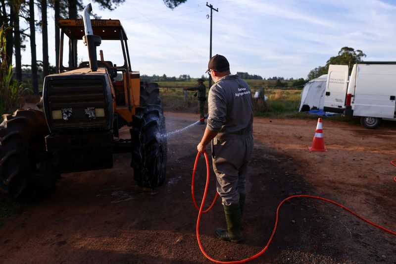 &copy; Reuters. Um homem limpa um trator em uma barreira sanitária, depois que o Brasil confirmou seu primeiro surto de gripe aviária na sexta-feira, desencadeando protocolos para uma suspensão comercial pela China, seu maior comprador, e restrições para outros gran